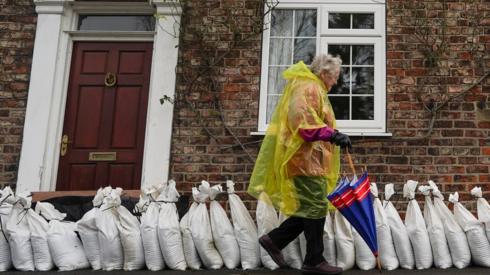 A woman walks past sand bag flood defences in the village of Naburn near York as water levels rise on the River Ouse.