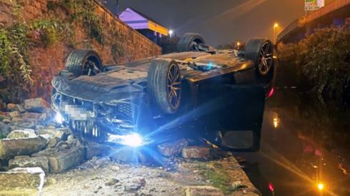 A car crashed through a wall and flipped on its roof next to a canal
