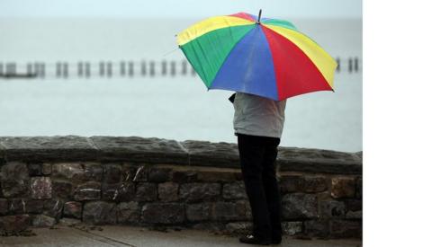 Woman shelters under umbrella