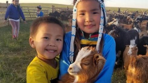 Two Mongolian children with a goat