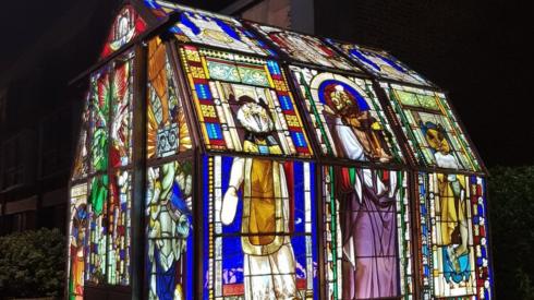 A lit greenhouse made out of stained glass