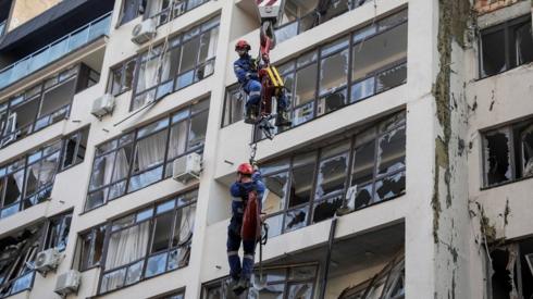 Rescue workers are elevated by a crane, at an apartment building