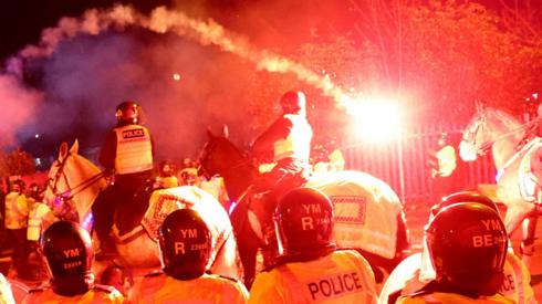 Legia Warsaw fans let off flares as they clash with police officers outside the stadium before the match on 30 November 2023