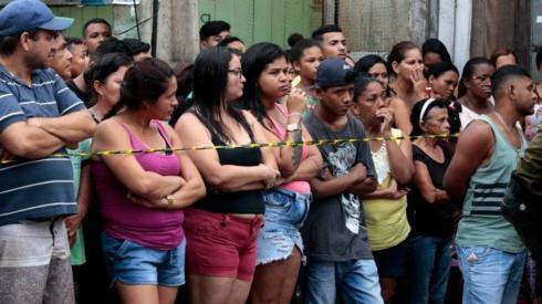 Residents gather outside a bar as forensic personnel and criminal police remove corpses after a shooting, in Belem, Para state, Brazil on May 19, 2019.