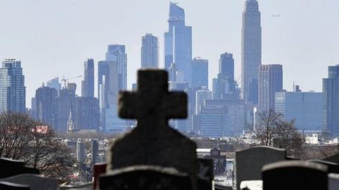 Gravestones from a cemetery are seen with the Manhattan skyline