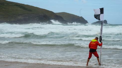Lifeguard puts out flag on Fistral Beach in Newquay, Cornwall amid Storm Evert, on 30 July 2021