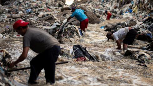 Men search for scrap metal in the polluted waters of the Las Vacas river