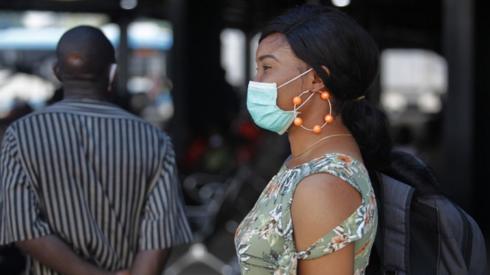 A woman wearing a surgical mask waits for a bus in Lagos, Nigeria