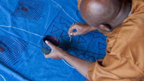 A craftsman making bogolan designs.
