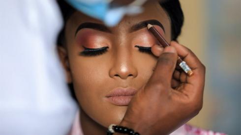A make-up artist applies brow pencil to a woman's face.