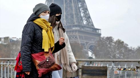 Women walk in front of the Eiffel Tower wearing Covid face masks, November 2021