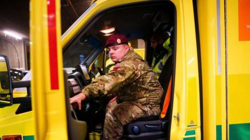A man in military uniform closes the door of an ambulance