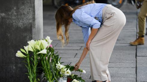 A woman places flowers outside the shopping mall
