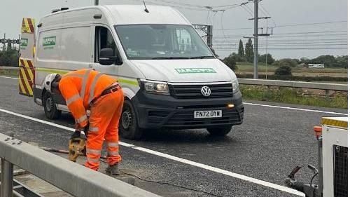 A workman working on a crash barrier on the A6, Bedfordshire