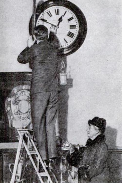 Belville supervising the setting of an office clock