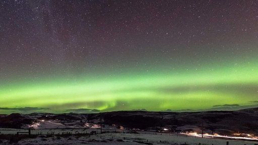 Green glow from Northern Lights over snowscape