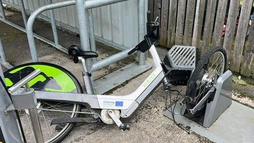 A smashed up electric bike in a docking station
