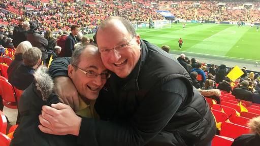 Jon Burns hugs a friend while in the stands at Wembley Stadium