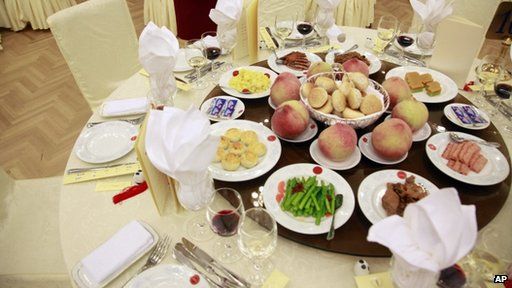 A waitress stand next to a table of food prepared for a National Day reception at the Great Hall of the People on the eve of the Oct. 1 National Day in Beijing
