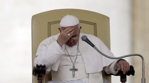 File photo: Pope Francis touches his forehead after delivering his message during the general audience in St. Peter's Square, at the Vatican, 9 April 2014