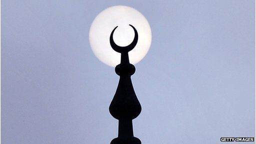 A minaret silhouetted against the moon