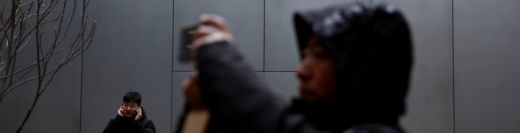 People use their phones outside an Apple store in Beijing, China January 7, 2019.
