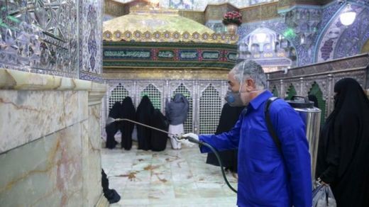 Petugas menyemprotkan disinfektan di kuil Hazrat Masumeh di kota Qom