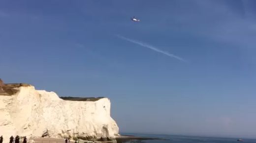 A helicopter hovers over the fallen cliff at Seaford Head, East Sussex