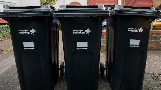 Three black wheelie bins on a road