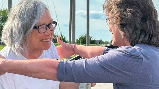 A smiling Sandra Hemme walks out of prison and into the arms of a female family member who is also smiling.