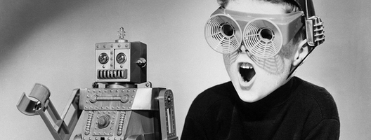 A black and white image of a retro robot and a boy with futuristic glasses on