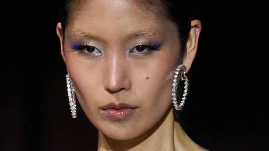 Model at New York fashion week on the runway wearing blue mascara and silver earrings 