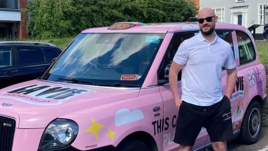 Matthew Murphy standing next to pink taxi