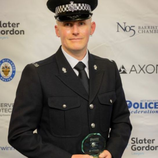 PC Brabham dressed in his uniform, holding a police award