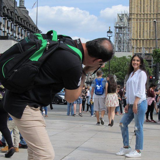 A man bending over to take a woman's photograph