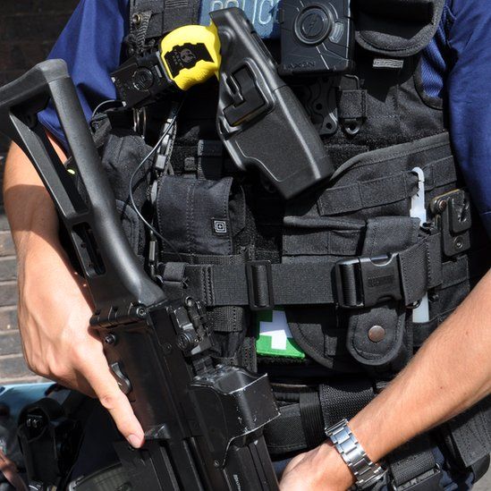 Armed British Police officer, with rifle and Taser, wearing a body-worn video camera