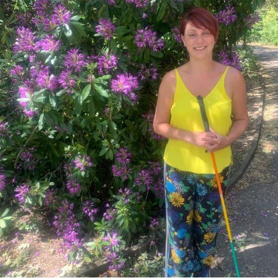 Nina Chesworth standing outside in front of a bush with purple flowers