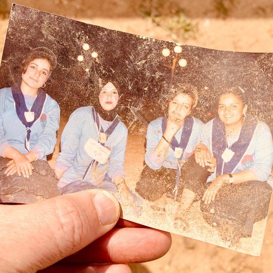 A photograph, shown in a hand, shows four women