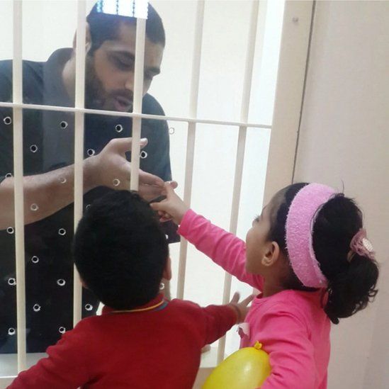 Mohamed Ramadhan reaching through bars to two children
