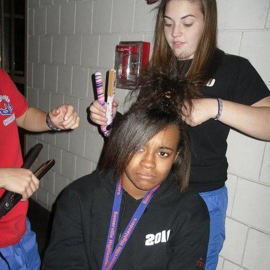 Tameka Amado gets hair straightened by teammates for cheerleading squad