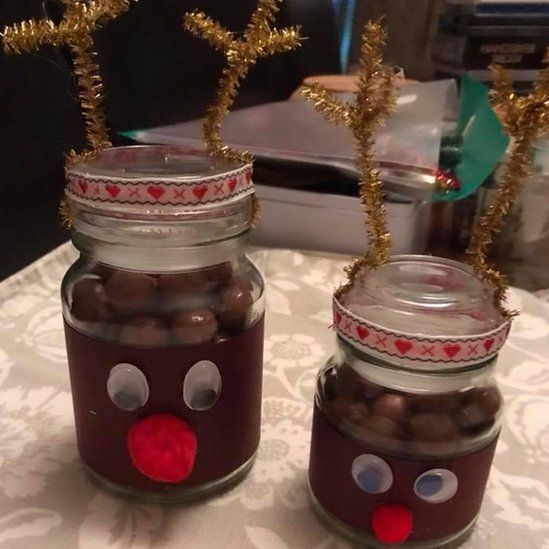 Two empty coffee jars refilled with chocolates and decorated with glitter horns, and red noses