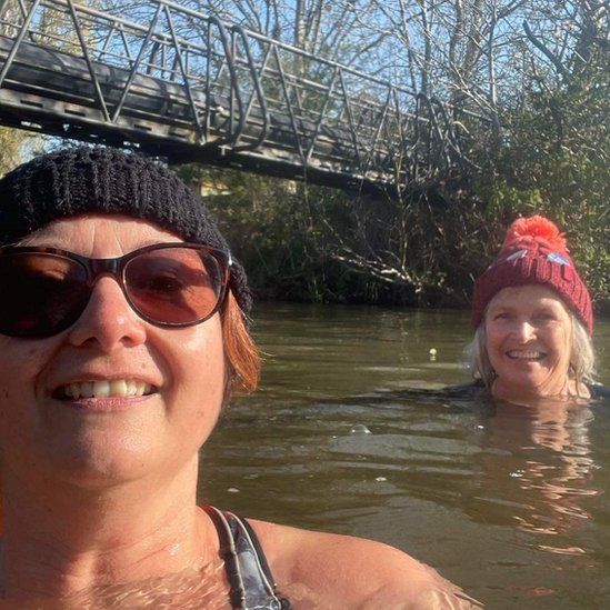 Women in woolly hats swimming in river