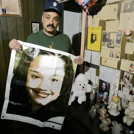Felix DeJesus holding a banner showing a photograph of his daughter Gina in 2004