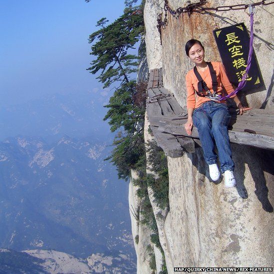Woman poses on Chang Kong Cliff Road in Shaanxi province, China