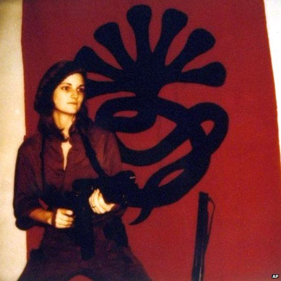 Patty Hearst in front of the Symbionese Liberation Front logo