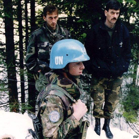 A Dutch UN peacekeeper standing near two unidentified Bosnian men in Srebrenica (1994)