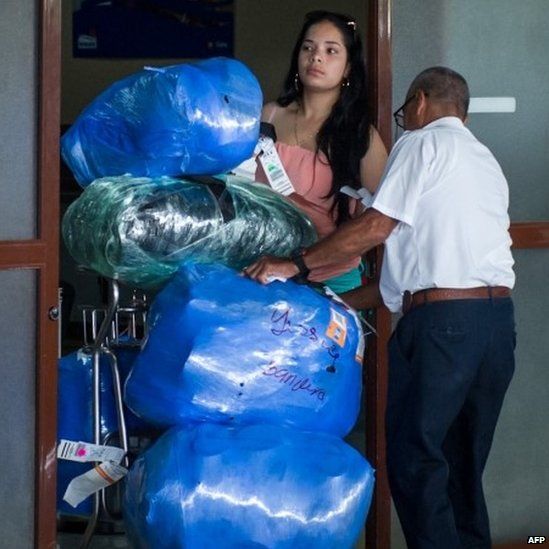 An airport worker checks large bundles carried on a cart by a woman at Havana's airport. Photo: August 2014