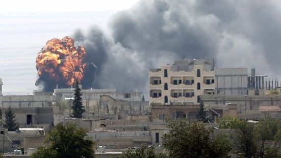 Flames and smoke rise from a building in the Syrian town of Kobane after it is hit by shellfire (3 October 2014)