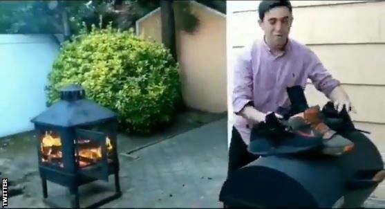 An unknown man burns Nike trainers