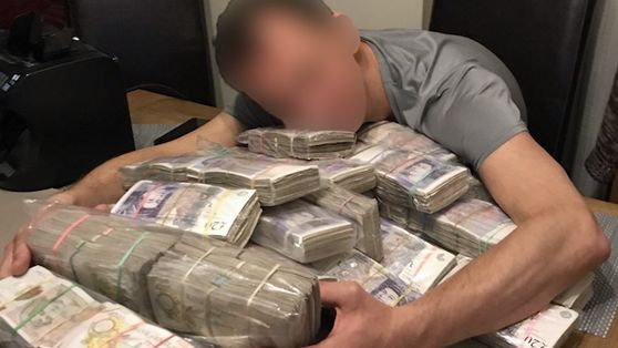 One of the gang hugging a pile of bank notes